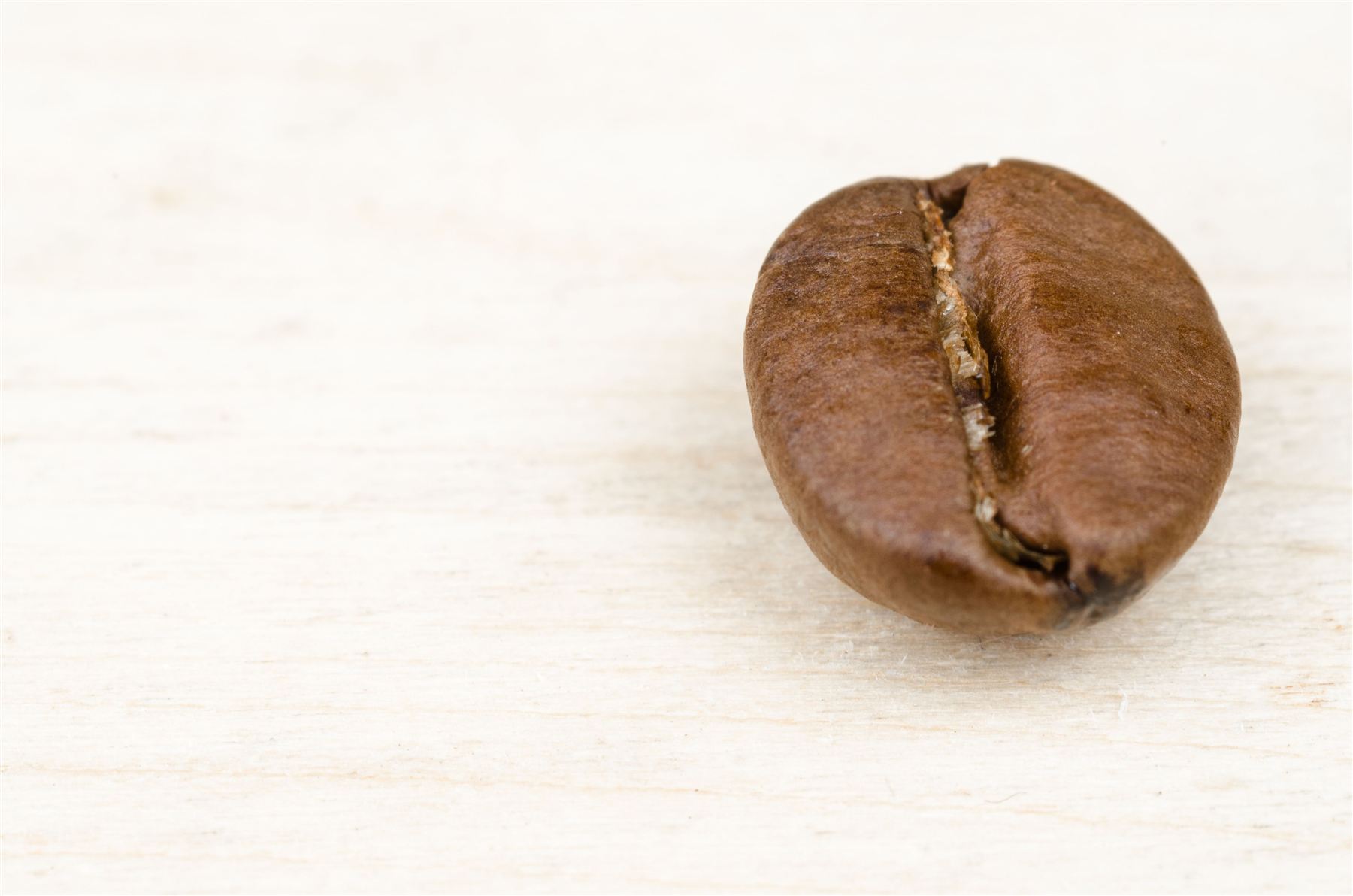 Einzelne Kaffeebohne auf hellem Holz