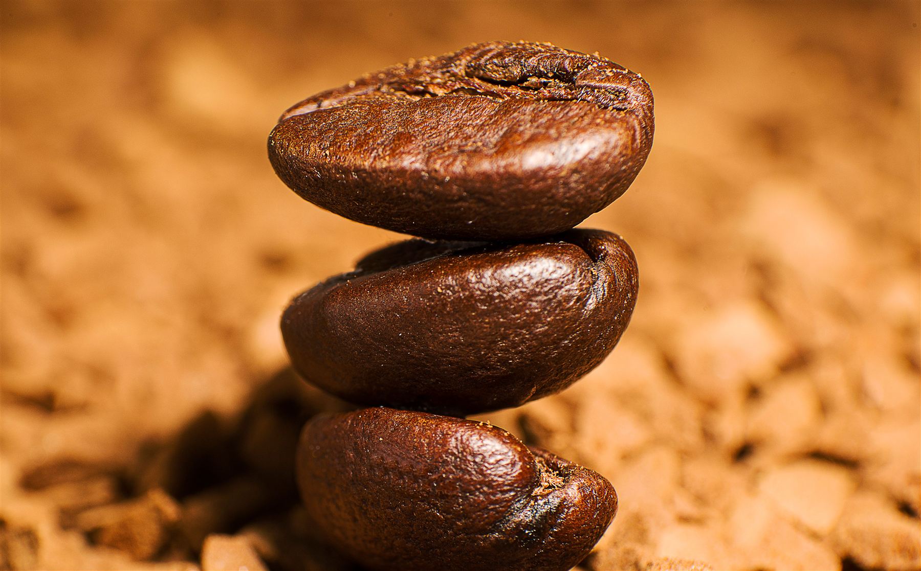 Drei aufeinander gestapelte, frisch geröstete Kaffeebohnen